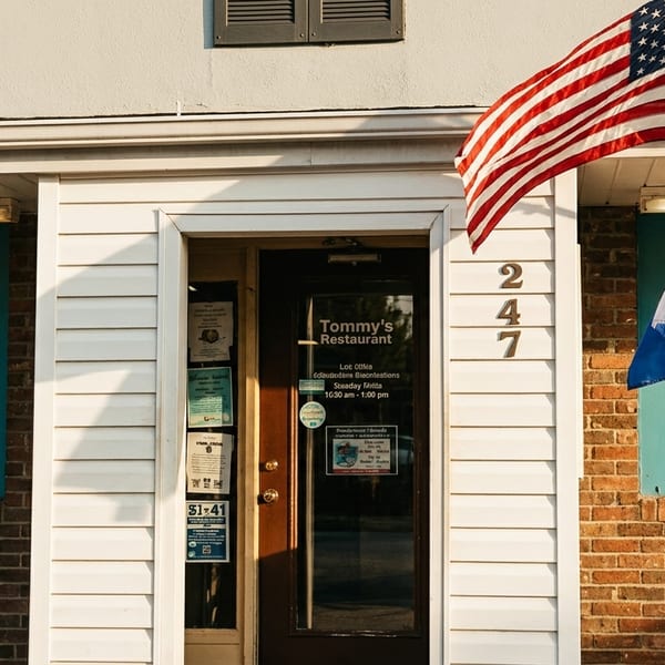 Tommy's Restaurant exterior with an American flag and a Greek flag flying next to the entrance.